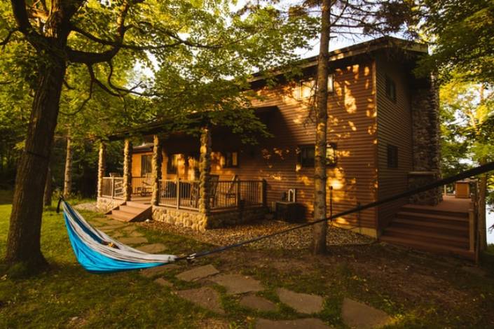 blue hammock hanging outside a wood cabin in dappled light