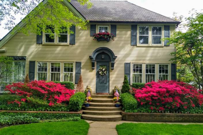 house with gardens in the front and two American flags